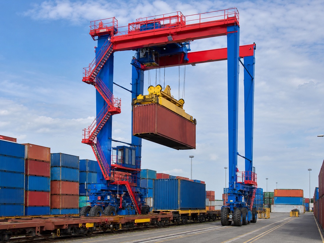 Rubber-tyred gantry crane straddling a row of stacked shipping containers